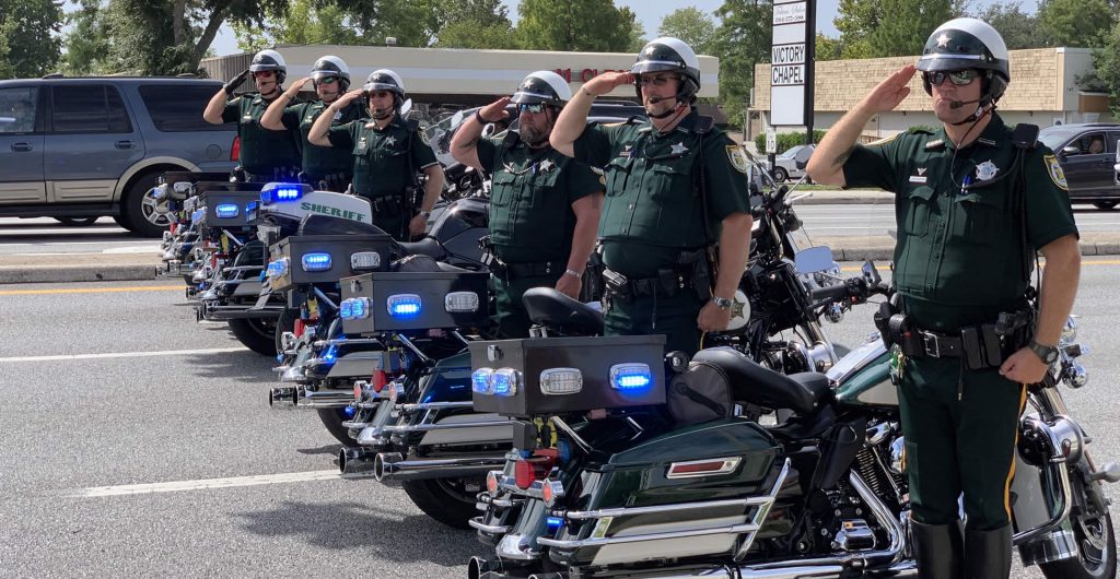 Deputies saluting next to their motocycles